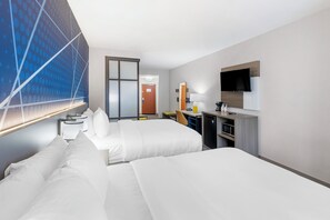 A hotel room with two beds, a desk with a computer, a TV, and a large window with a geometric design. - Comfort Suites Pecos (Pecos)
