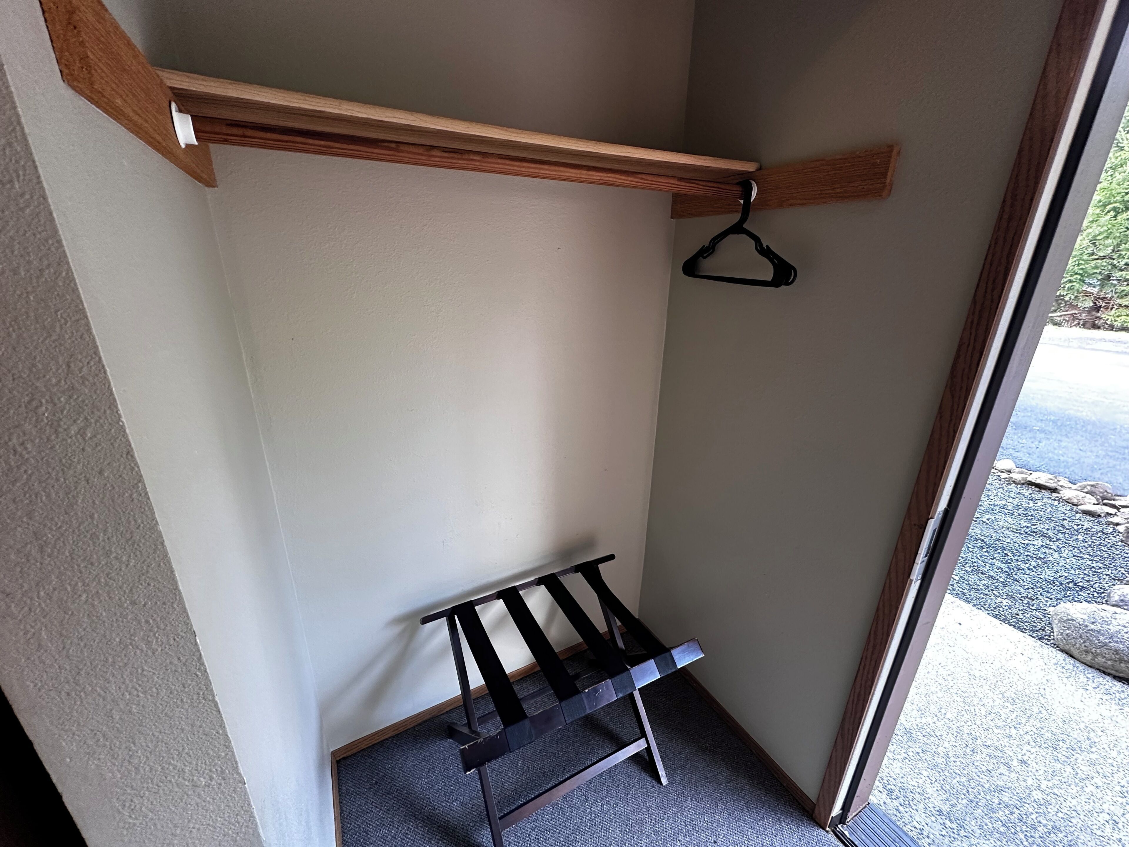 Rincón de una habitación con techo de vigas de madera, una estantería de metal negro y una puerta que da al exterior.