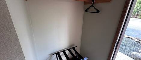 Rincón de una habitación con techo de vigas de madera, una estantería de metal negro y una puerta que da al exterior.
