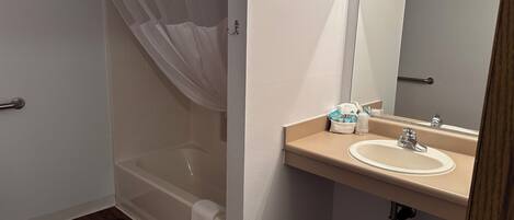 A bathroom with a bathtub, a sink, and a mirror.