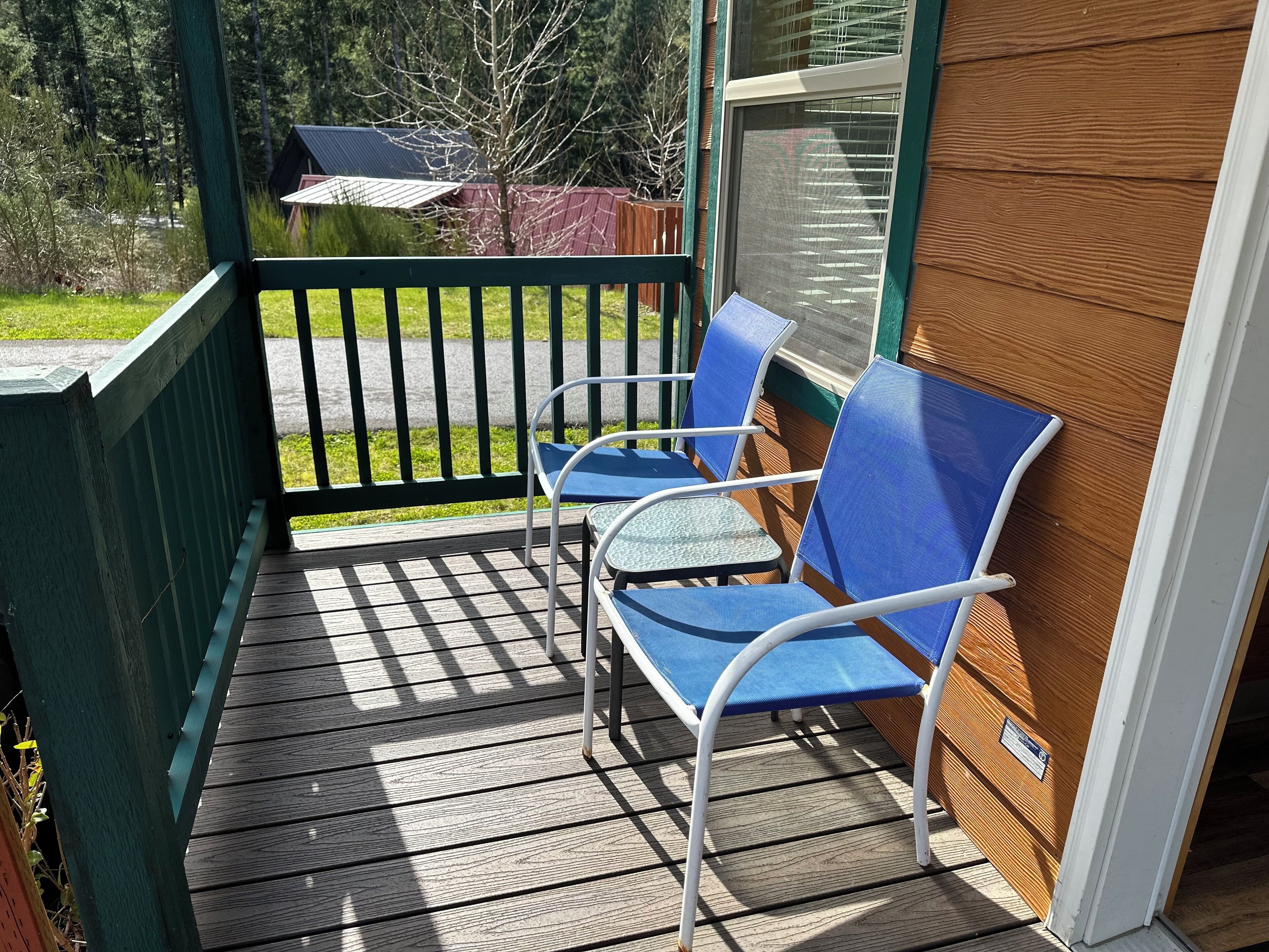 A porch with two blue chairs and a wooden deck.