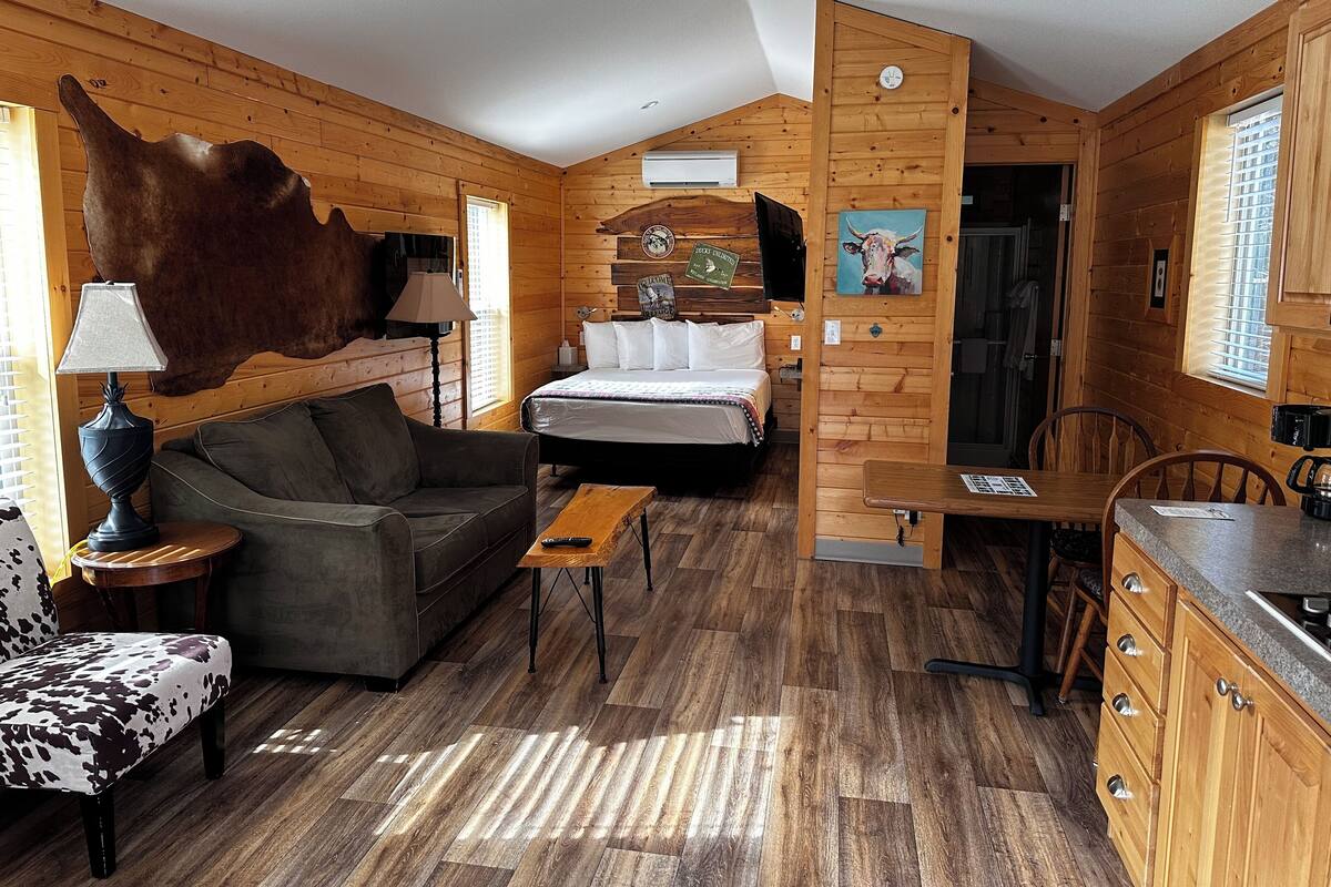 Ein gemütliches Blockhauszimmer mit Bett, Sofa und Essecke.