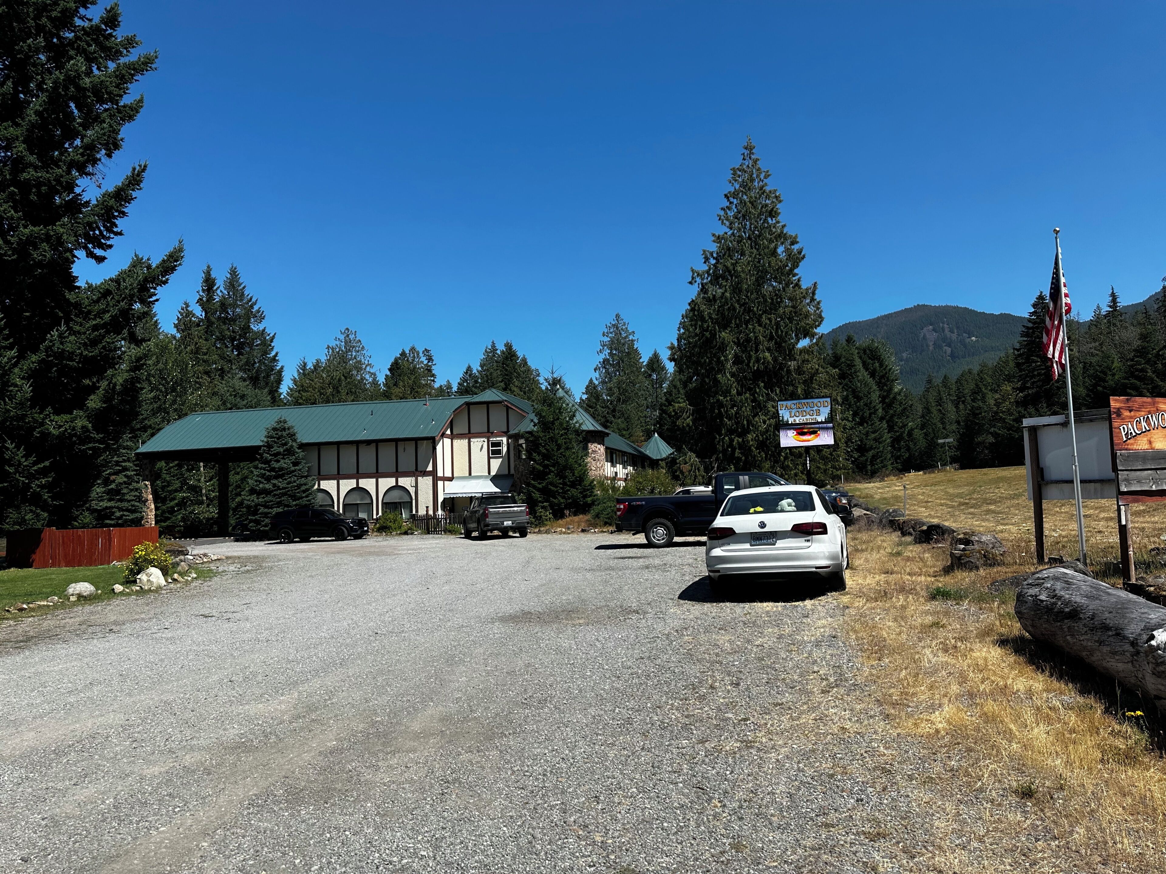 A lodge with a green roof, a covered parking area, and a signboard.
