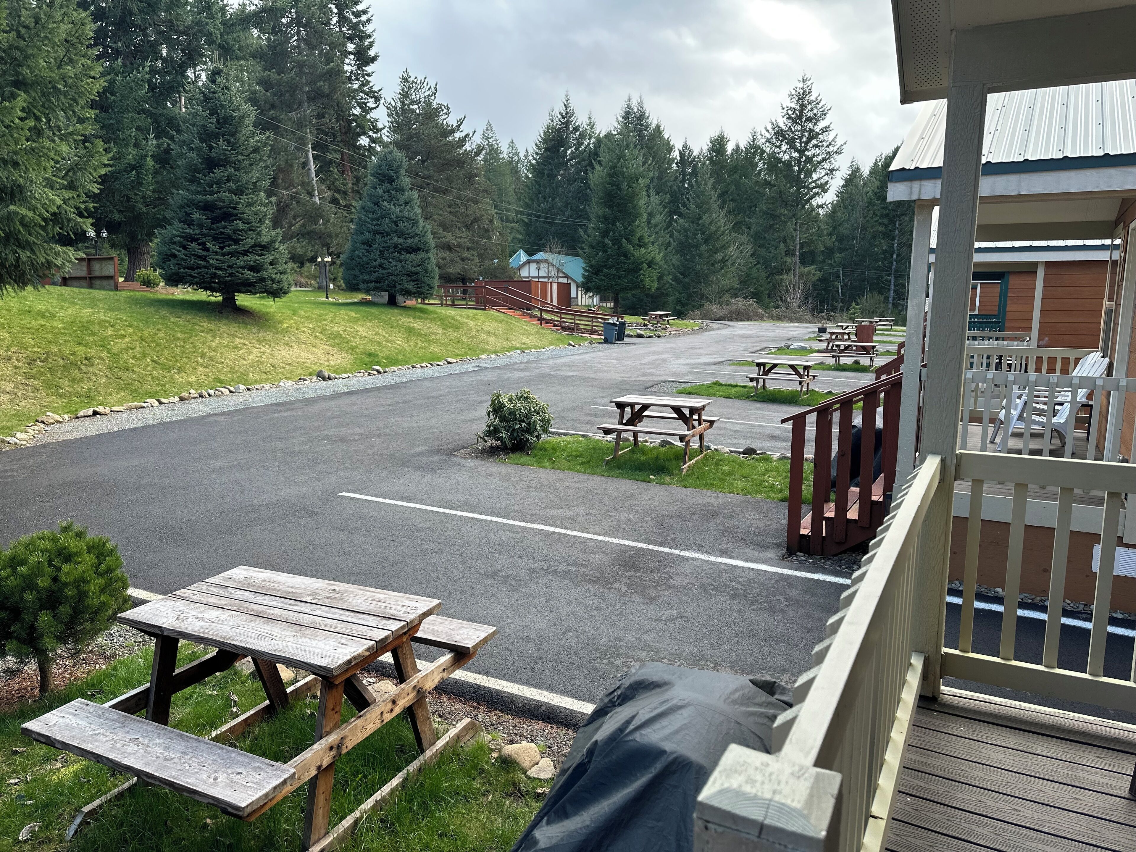 En campingplads med picnicborde, et overdækket picnicområde og en bygning med veranda.