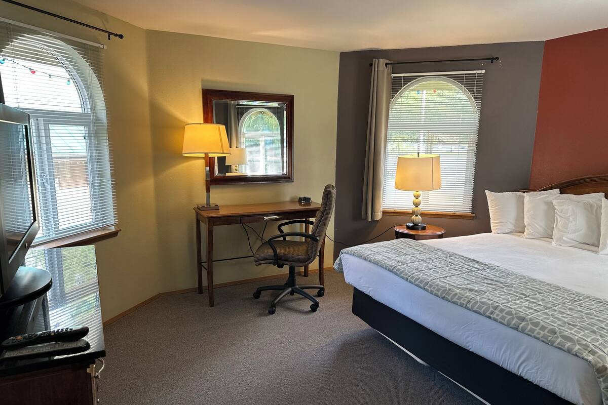 Ein Hotelzimmer mit Bett, Schreibtisch, Stuhl und zwei Lampen.