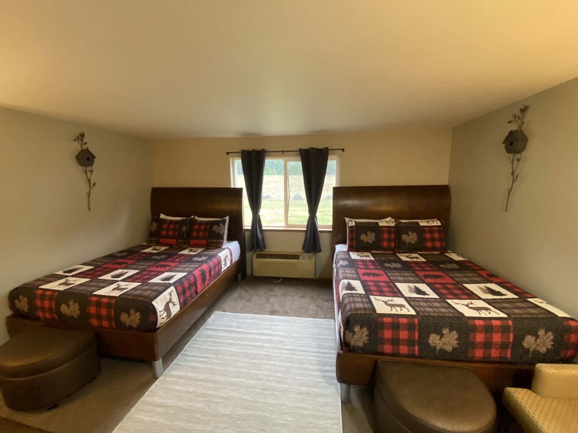 A room with two beds, a window with curtains, a heater, and wall decorations.