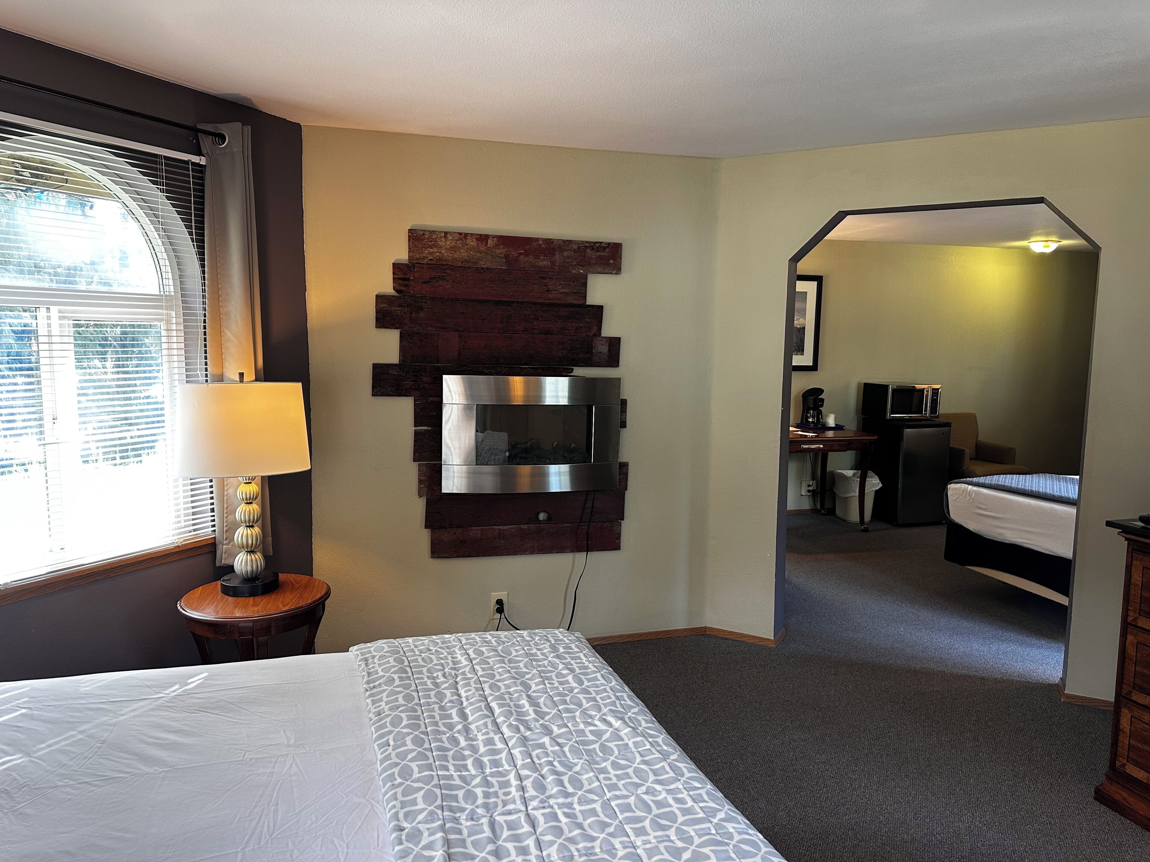 A hotel room with a bed, a TV mounted on the wall, a desk with a chair, and a microwave.
