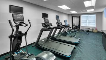 A fitness center with treadmills, elliptical machines, and stationary bikes, equipped with digital screens and heart rate monitors.