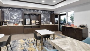 Une cuisine moderne avec des meubles de couleur sombre, un bar pour prendre le petit-déjeuner et un coin repas comprenant une table et des chaises.