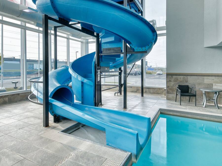 Una piscina interior con un tobogán de agua azul y vista al aeropuerto.