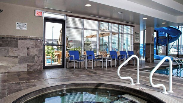 Un espace piscine de forme circulaire, avec des sièges disposés autour de la piscine et une porte de sortie.