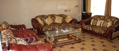 A living room with two patterned sofas, a glass coffee table, and a patterned carpet.