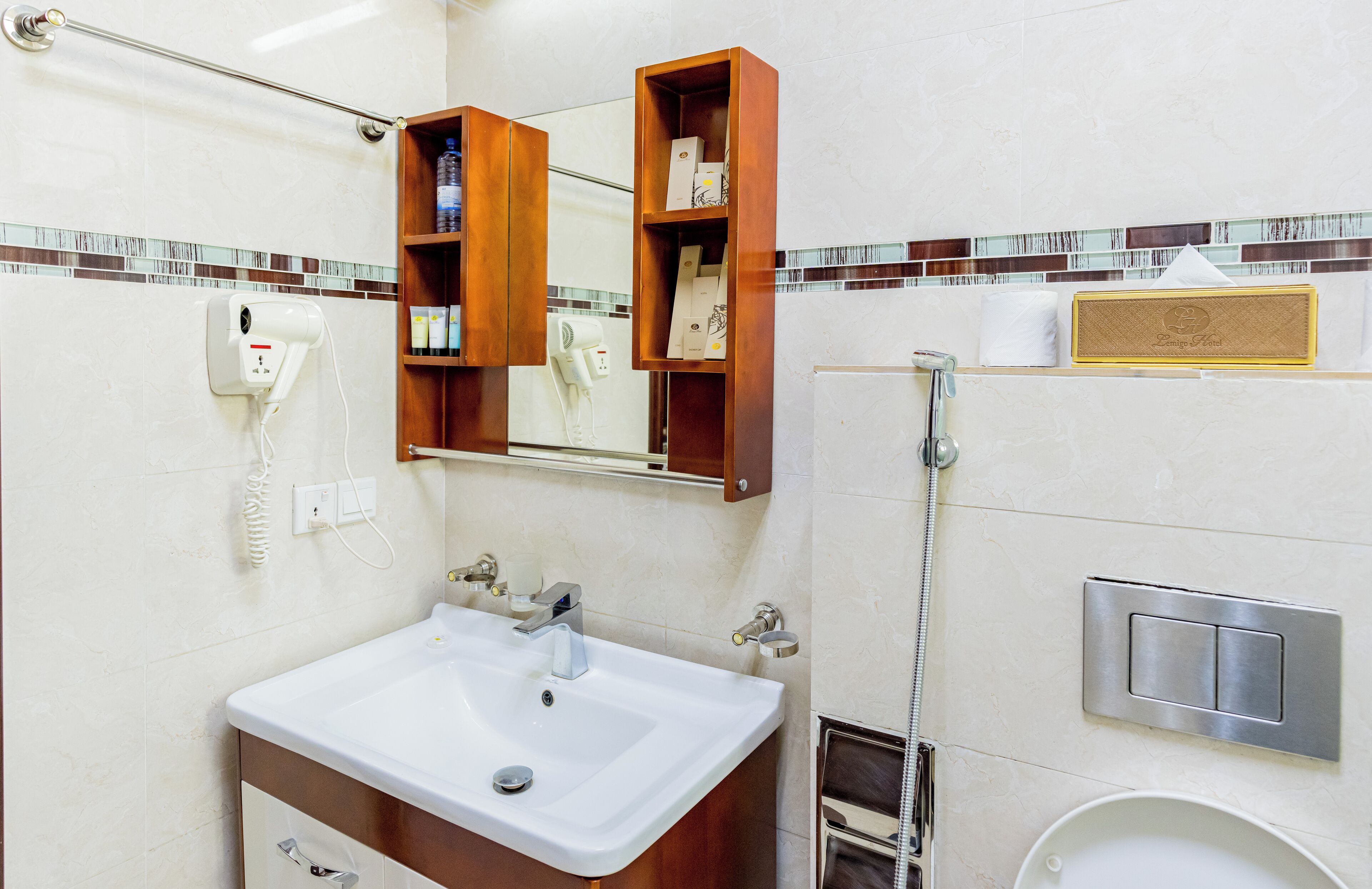 A bathroom with a white sink, a mirror, a towel rack, a hand dryer, and a toilet.