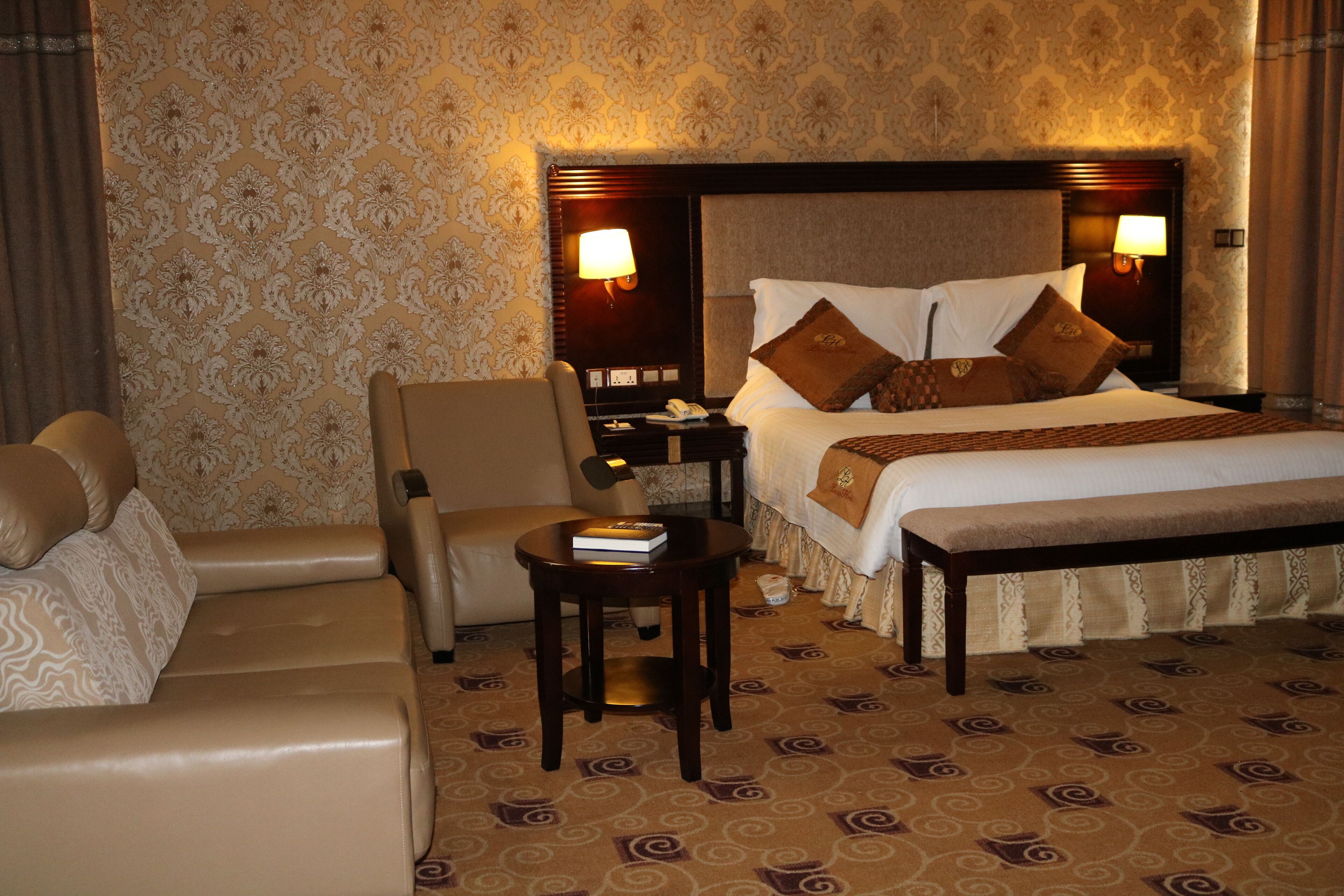 Una habitación de hotel con una cama grande, una mesita de noche, una silla y una pequeña mesa.