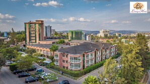 A multi-story hotel with a central courtyard, surrounded by greenery and parking spaces.