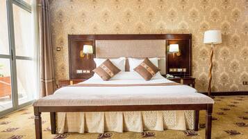A large bed with a wooden headboard, two bedside lamps, and patterned wallpaper.