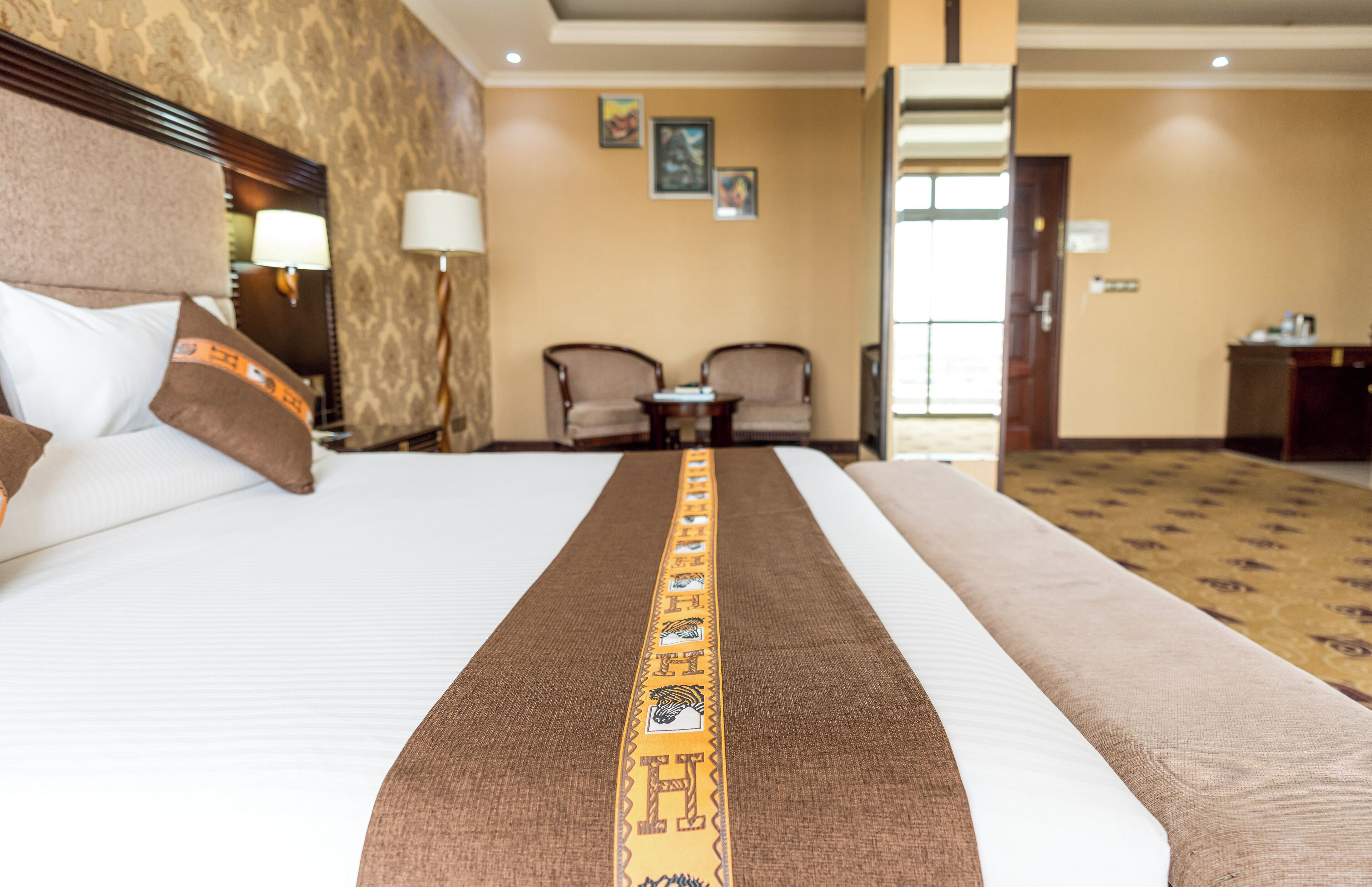 A hotel room with a large bed, two armchairs, a small table, and a desk.