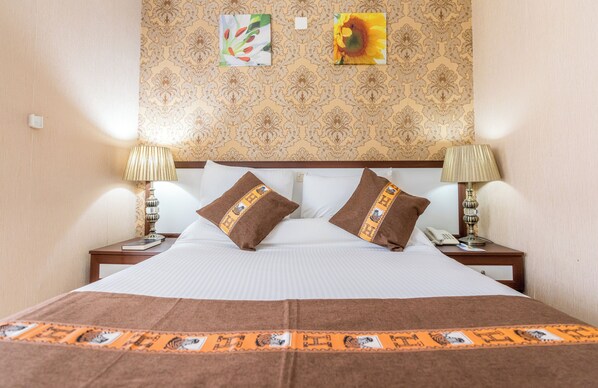 A hotel room with a large bed, two nightstands, a telephone, and two lamps.