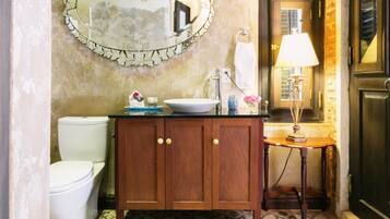 Un baño con suelo de baldosas, un mueble de madera, un lavabo, un espejo y un inodoro.