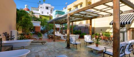 Un patio con mobiliario exterior, una pérgola y una bañera grande.