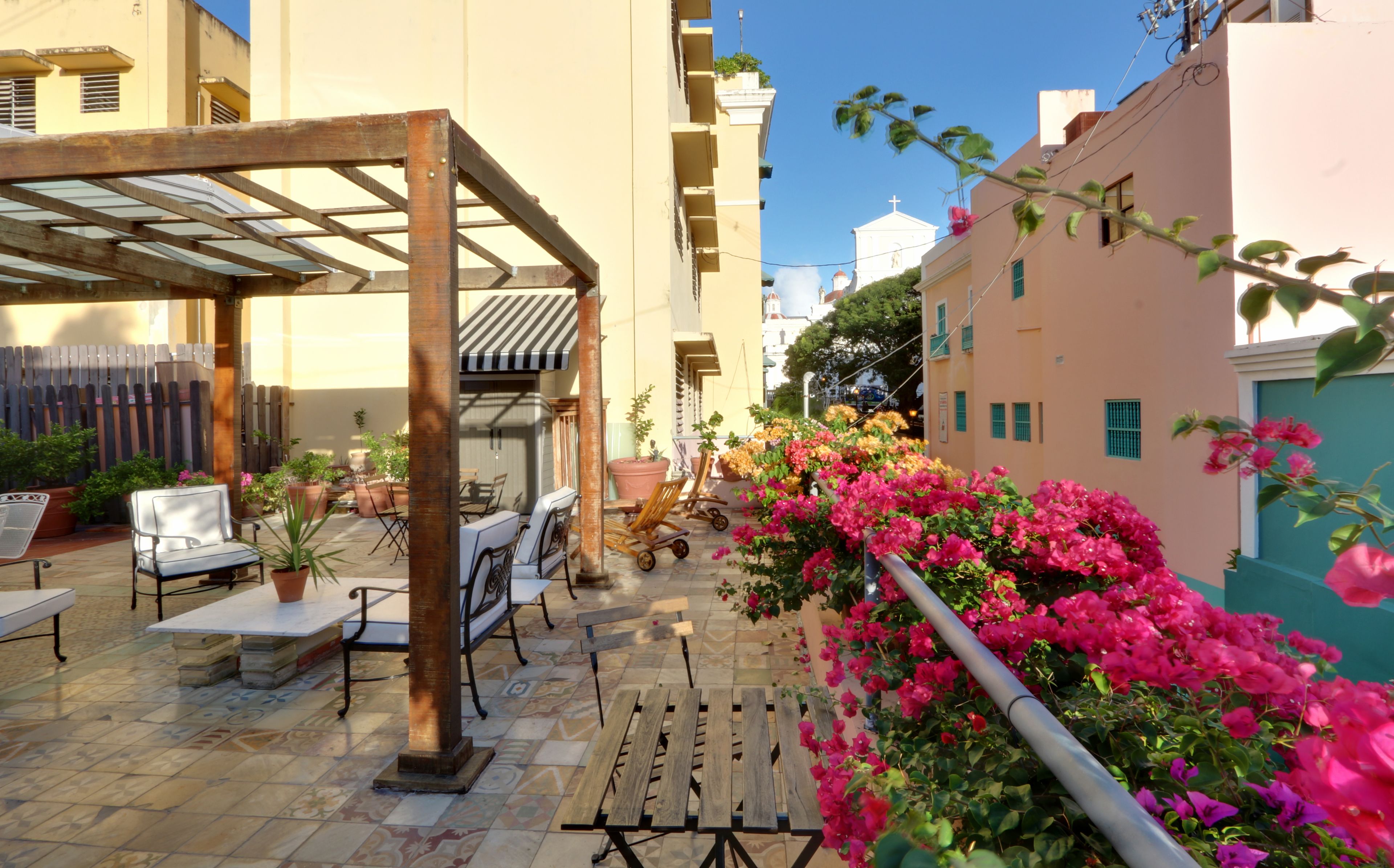 An outdoor patio area with a pergola, seating, and potted plants.