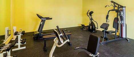 A gym with exercise equipment, a treadmill, and a bench.