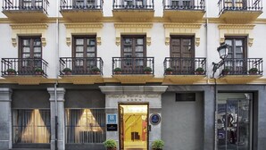 Een hotelgevel met meerdere balkons, grote ramen en een opvallende ingang.