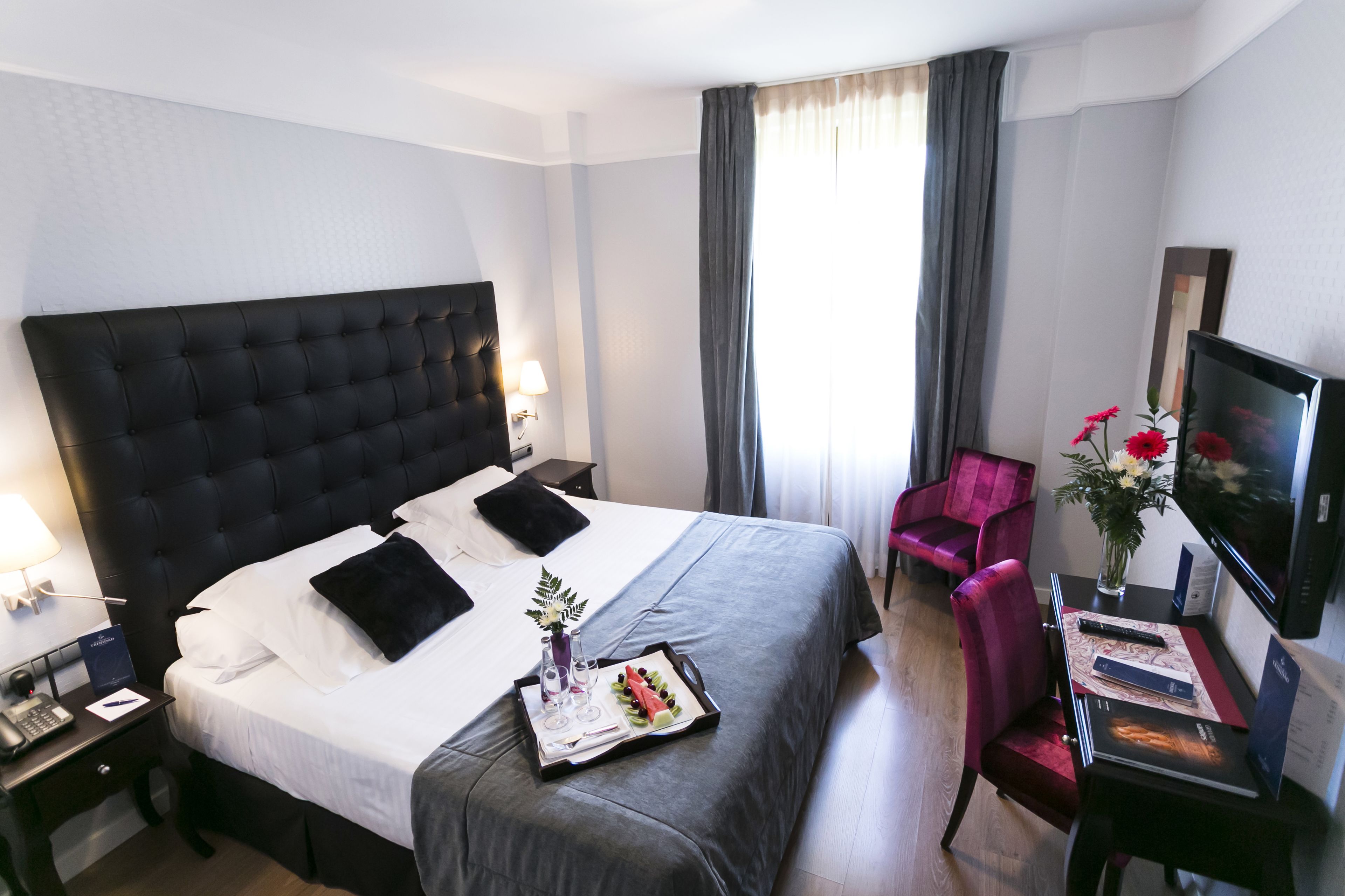 Una camera d'albergo con un letto grande, una scrivania con un computer, una sedia e una televisione.