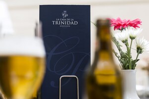 Egy üveg bor, egy virágos váz és egy tábla, amelyen a „La Casa de la Trinidad Granada” felirat szerepel.