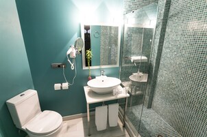 Egy fürdőszoba, amelyben WC, mosdókagyló, tükör és zuhanyzó található.
