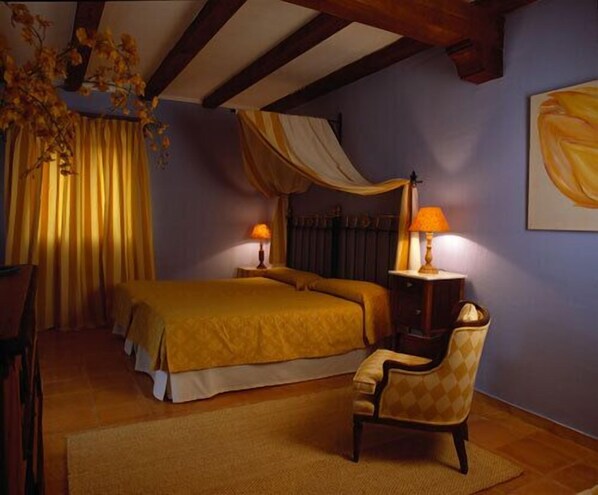 A bedroom with a large bed, two bedside tables, a chair, and a painting on the wall. - La Casita De Cabrejas (Cuenca)