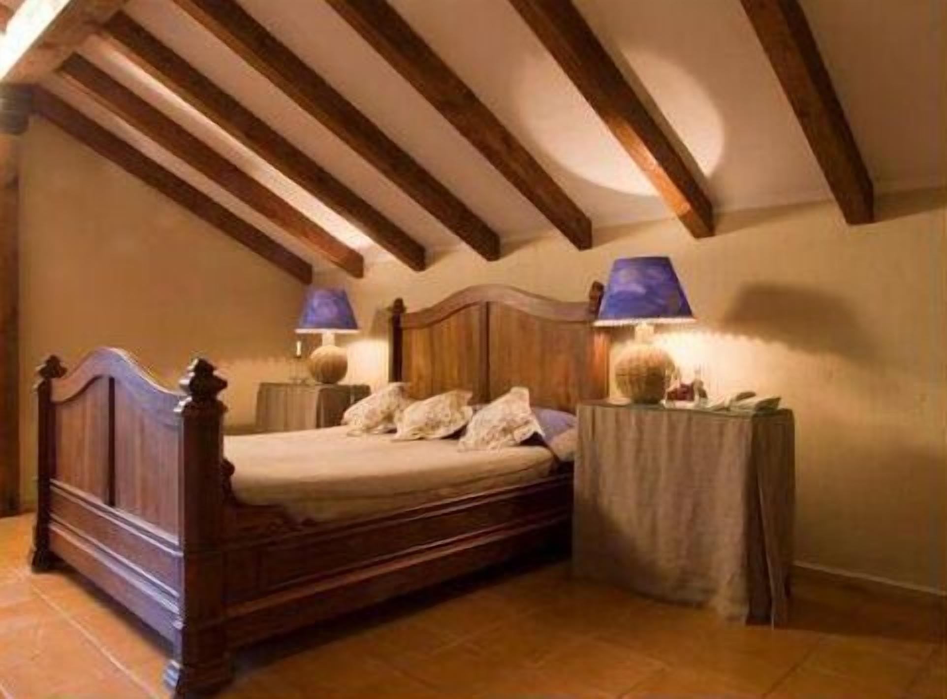 A bedroom with a wooden bed, two bedside lamps, and a nightstand.