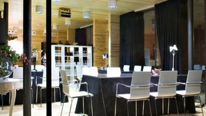 Ein Konferenzraum mit langem Tisch, weißen Stühlen und einem weißen Schrank mit Gläsern.