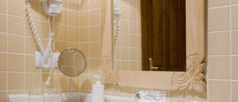 A bathroom with a white sink, two wall-mounted lamps, a mirror, and a towel rack.