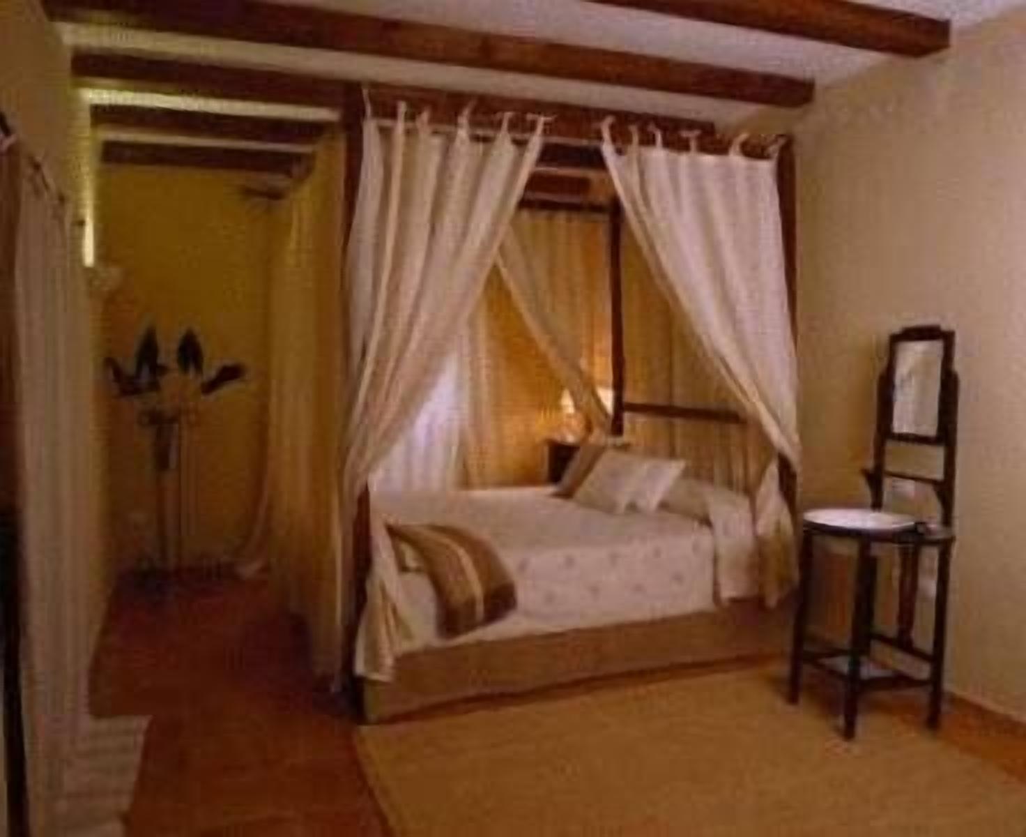 Un dormitorio con una cama, una silla y una mesita de noche.