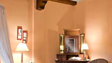 Habitación de hotel con cama, escritorio, silla, espejo y mesita de noche con lámpara.