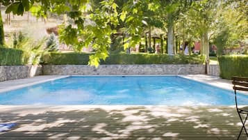 Een buitenzwembad, ligstoelen bij het zwembad