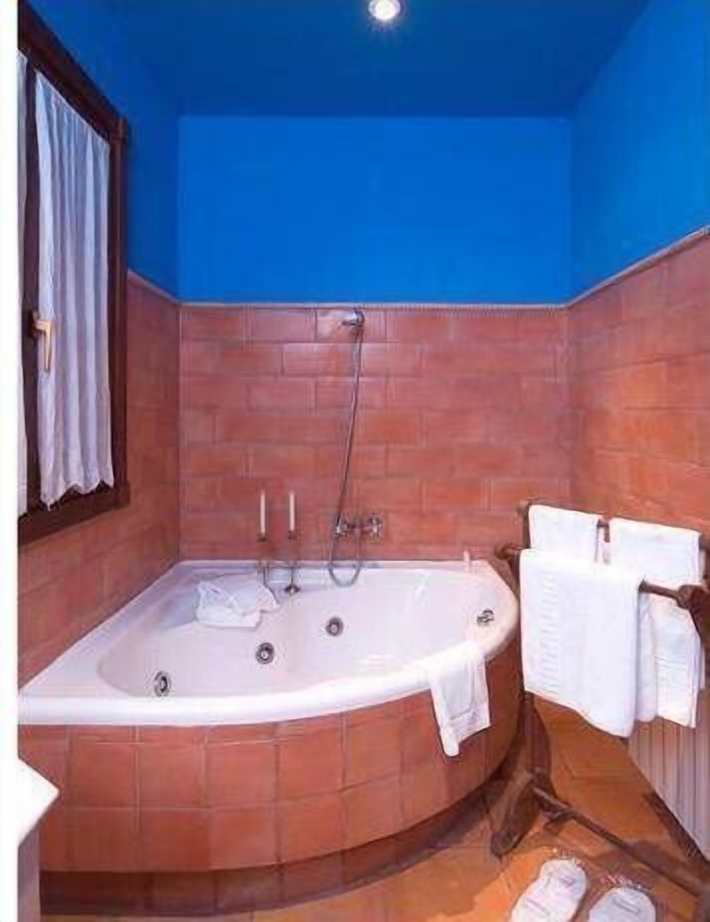 Une salle de bain avec une baignoire sur pieds, un porte-serviettes avec des serviettes et une fenêtre avec des rideaux.