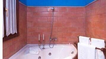 Une salle de bain avec une baignoire sur pieds, un porte-serviettes avec des serviettes et une fenêtre avec des rideaux.
