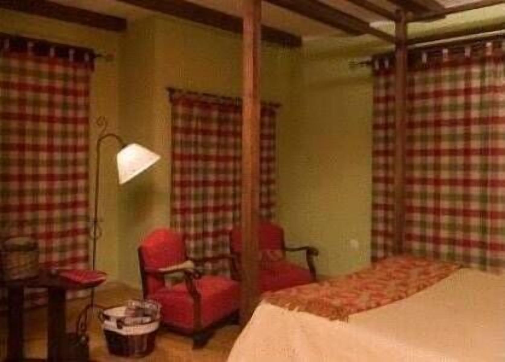 Una habitación con una cama, dos sillas, una mesa y una lámpara.
