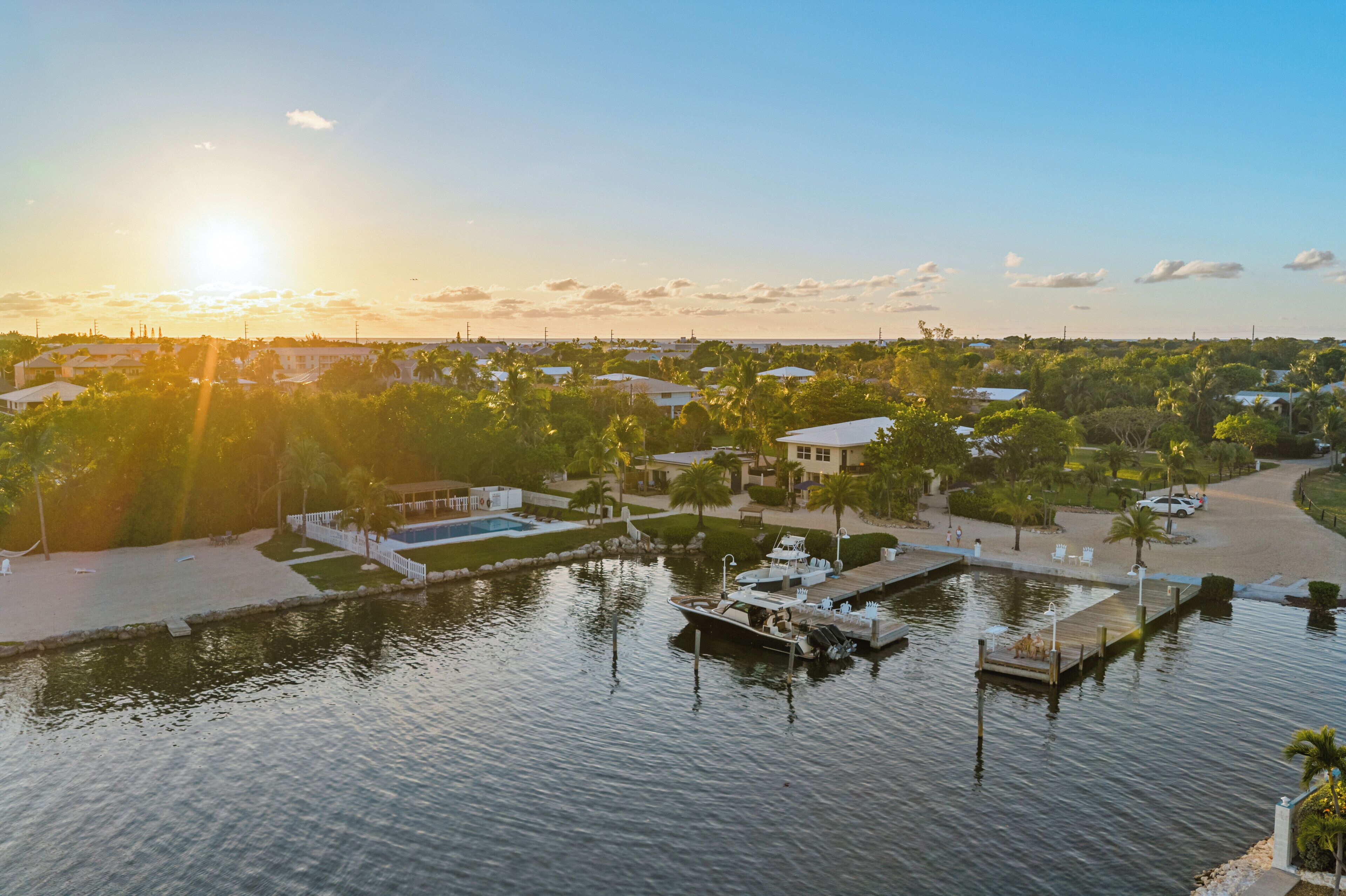 A marina with boats docked, a swimming pool, and a well-maintained landscape with trees and pathways.