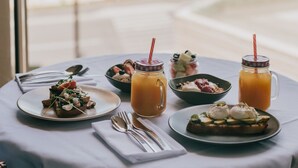 Ein Tisch mit Frühstücksangeboten und Getränken mit Blick auf einen Strand.