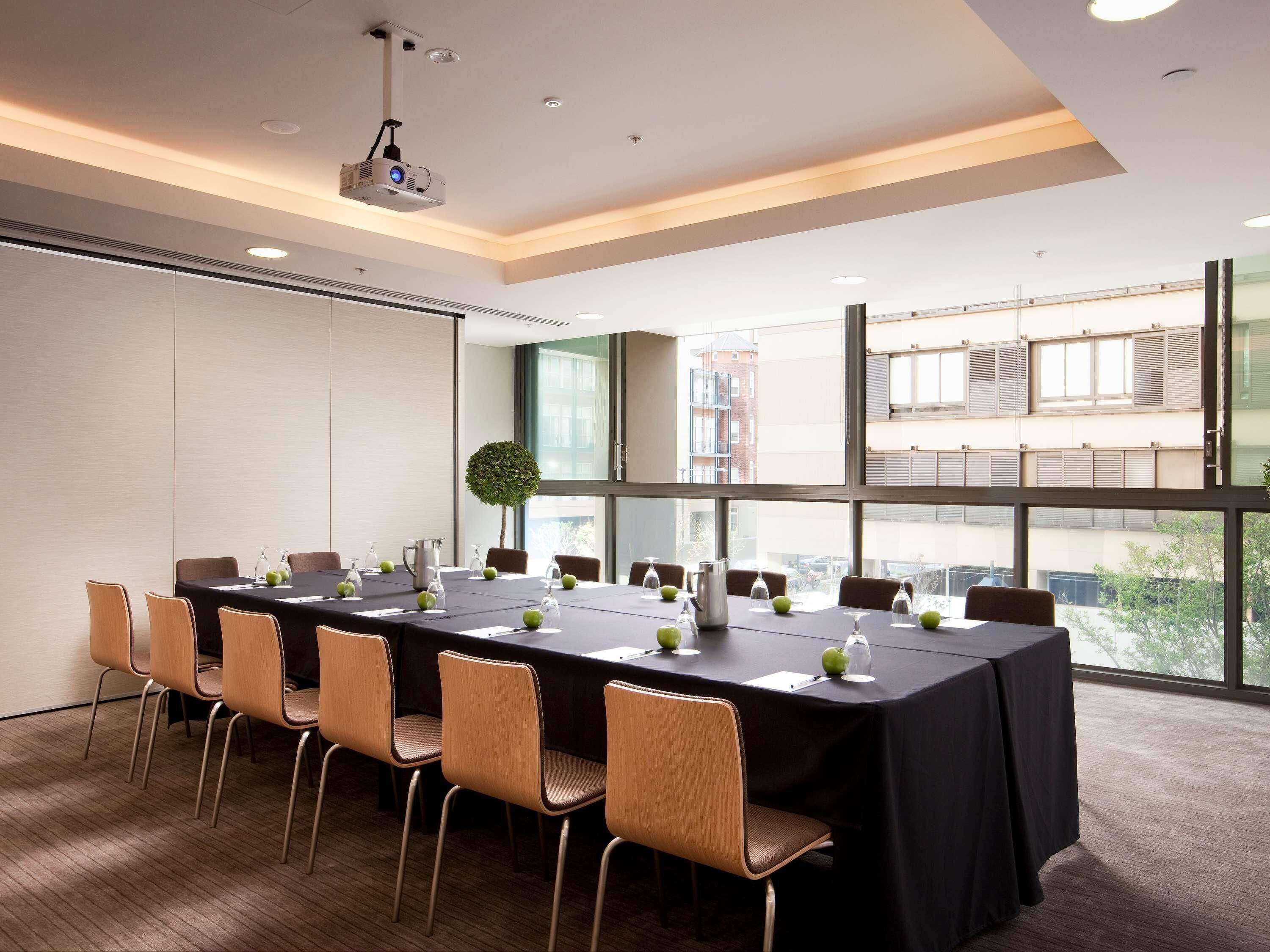 A conference room with a long table, chairs, a projector, and large windows.