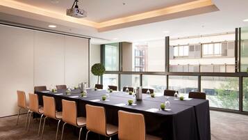 A conference room with a long table, chairs, a projector, and large windows.
