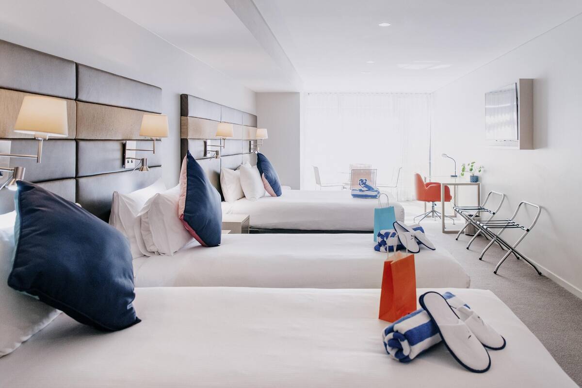 A hotel room with two beds, a desk, and a chair.