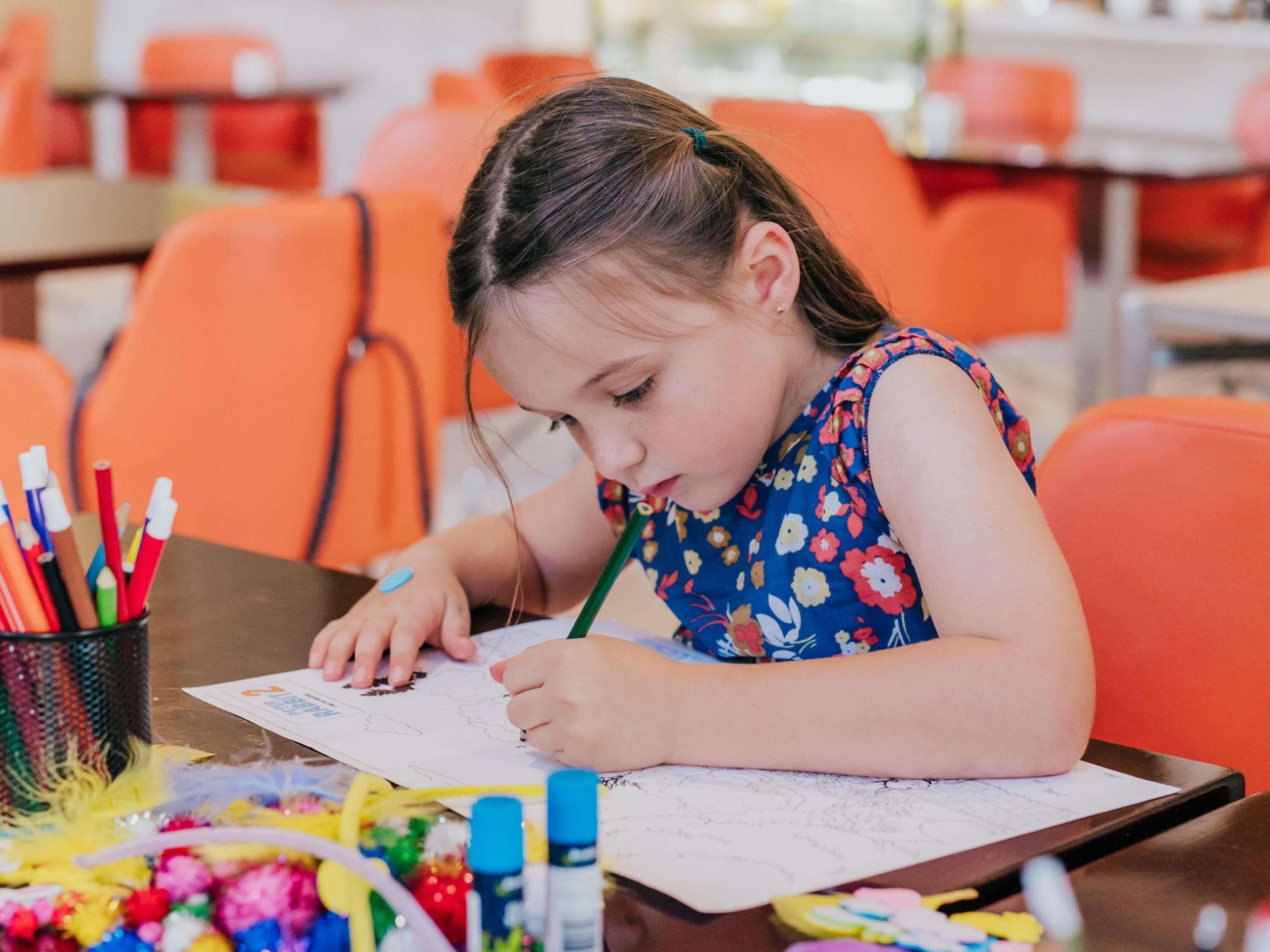 Un bambino disegna a un tavolo con materiali per l'arte.