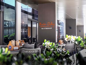 An outdoor seating area with wicker chairs, a Novotel sign, and a 'Bar & Restaurant' sign. - Novotel Newcastle Beach (Newcastle)