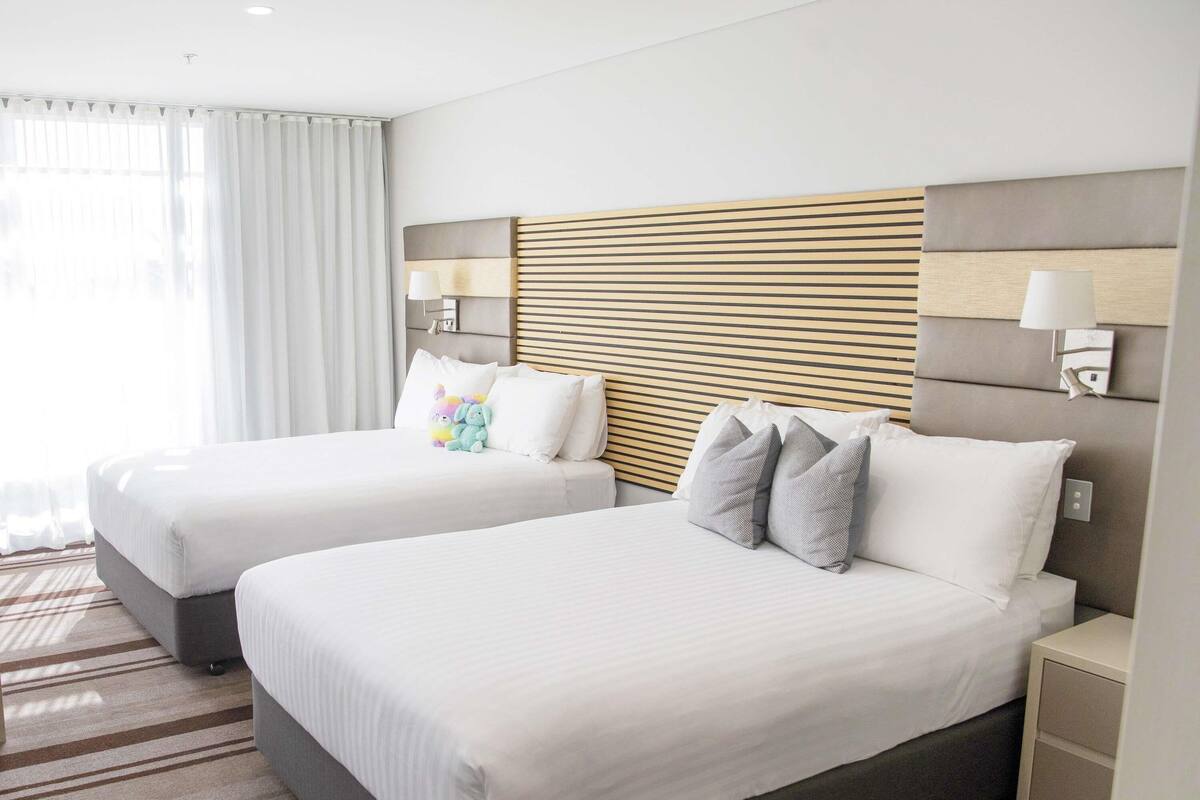 A hotel room with two beds, a striped carpet, and a modern headboard.
