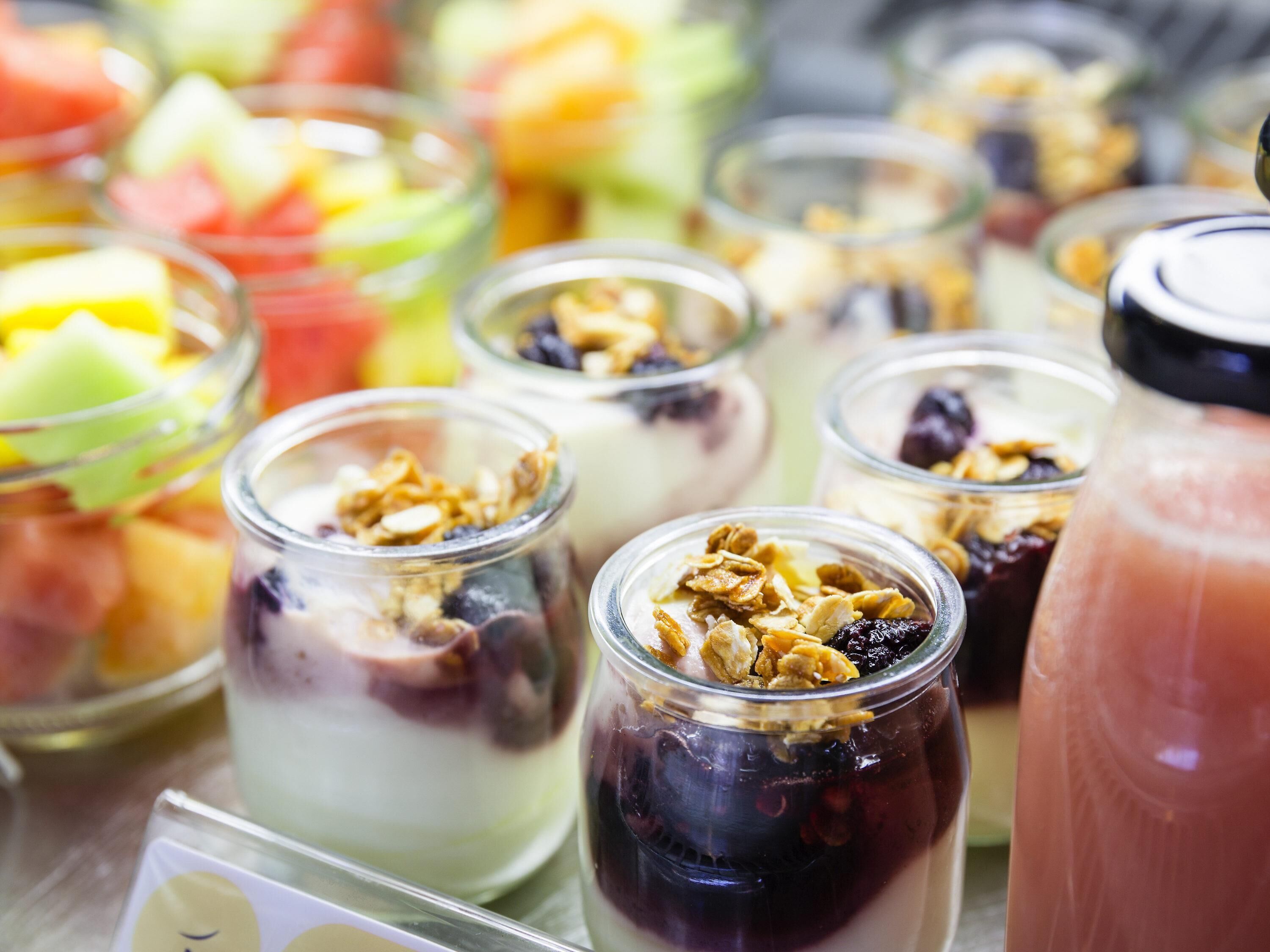 A variety of food items including fruits, yogurt, and granola in glass containers.