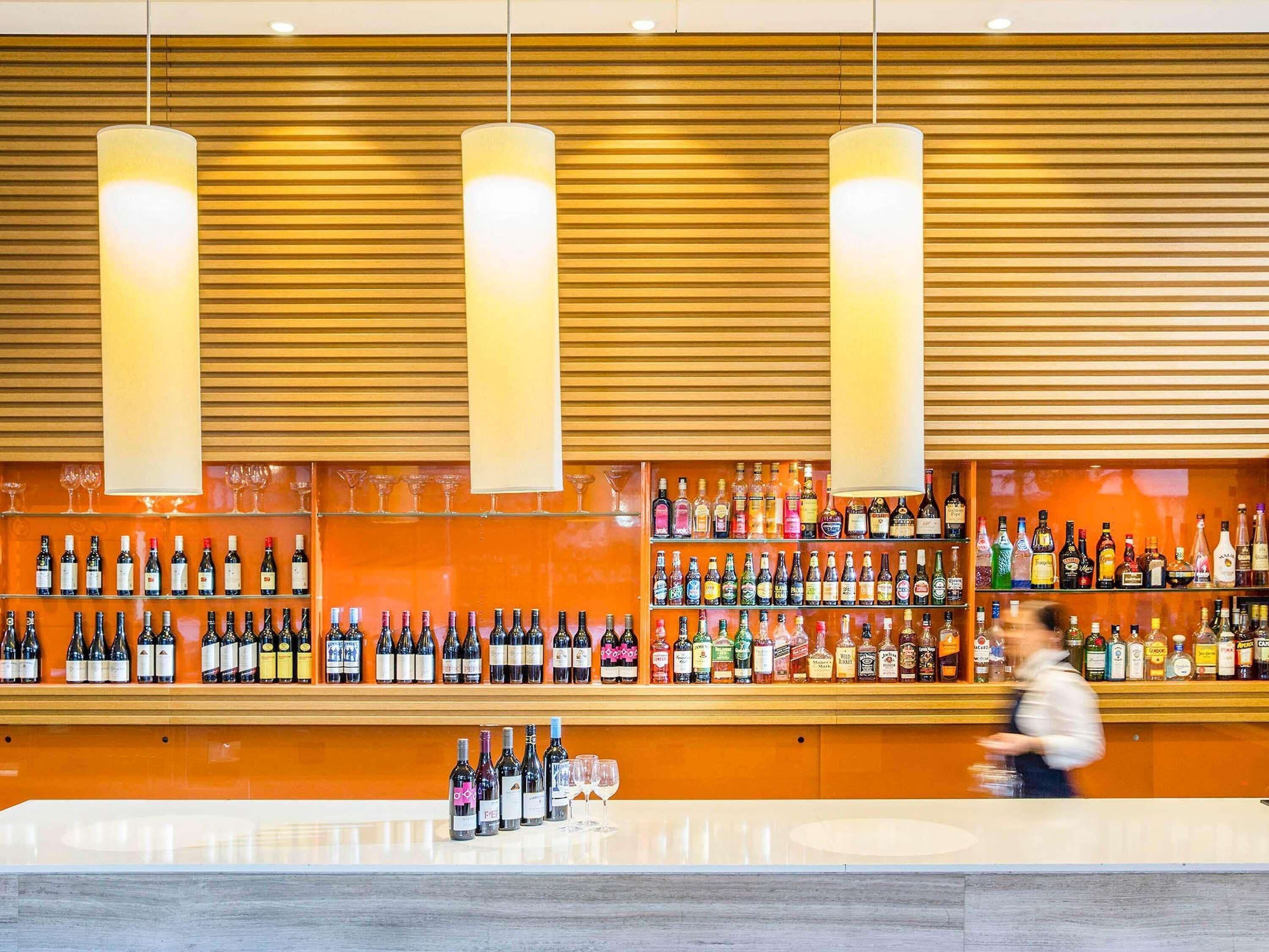 A bar with multiple shelves of alcohol bottles and glasses.